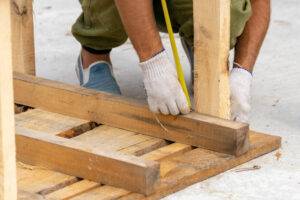 a person measuring a piece of wood