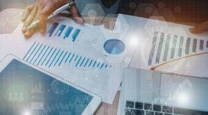 a person holding a pen and paper with graphs and charts