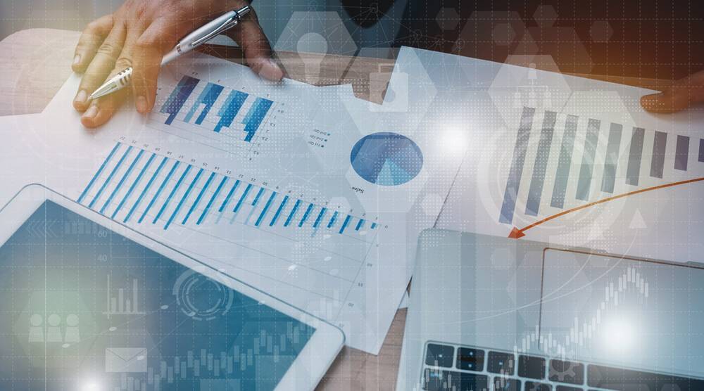 a person holding a pen and paper with graphs and charts