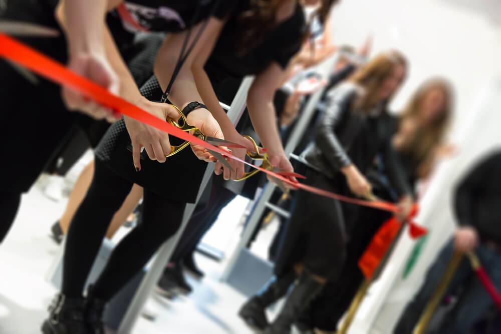 a group of people cutting red ribbon