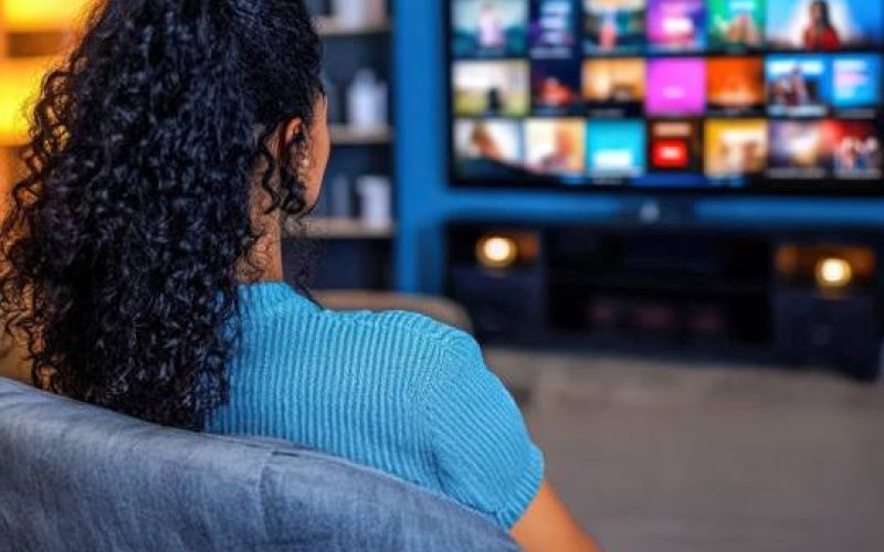 a woman sitting in a chair watching a television